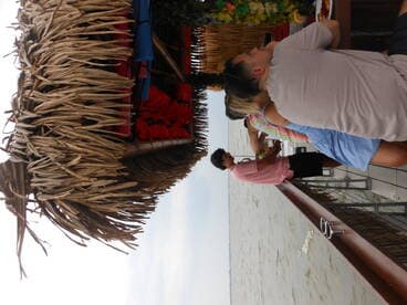 A lively group enjoys drinks and food at a waterfront dining area, perfect for socializing and relaxation on the water.