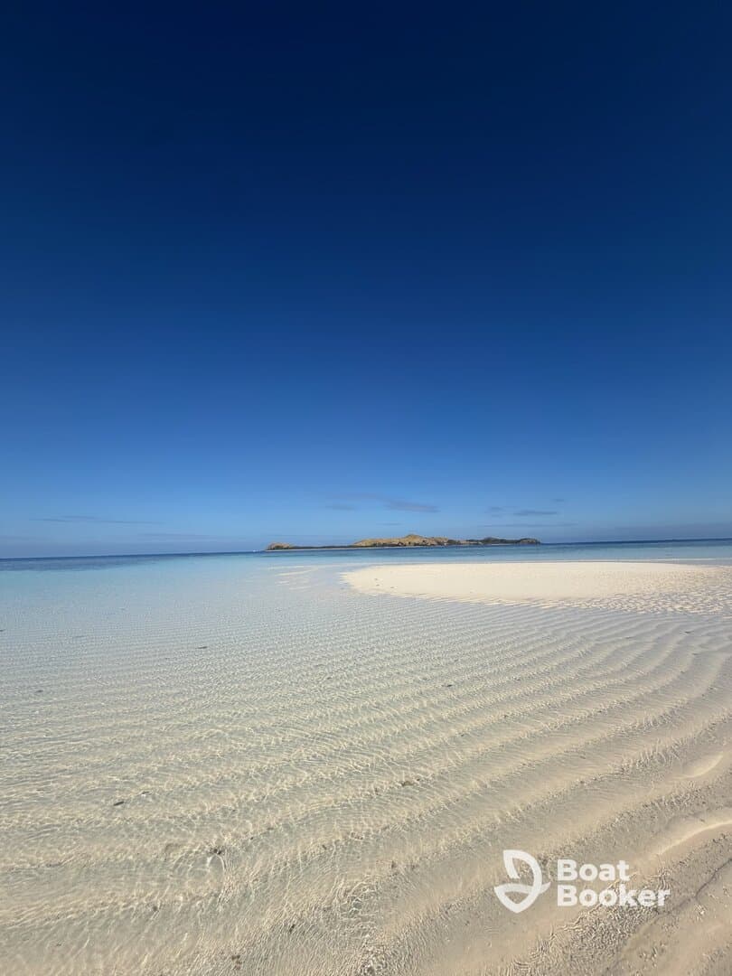 A stunning view of a serene beach with crystal-clear waters and a distant island, perfect for showcasing tropical destinations and tranquil getaways.