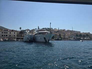 A stunning view of two luxurious yachts docked in a picturesque harbor, showcasing the charm of coastal architecture and clear blue waters.