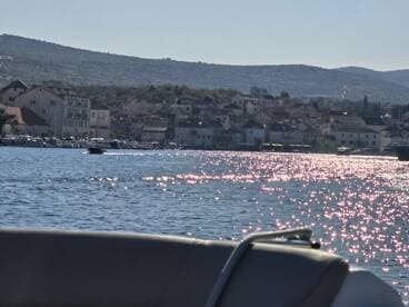 A picturesque view of a harbor with charming buildings along the coastline, reflecting sunlight on the water — a perfect backdrop for a boating adventure.