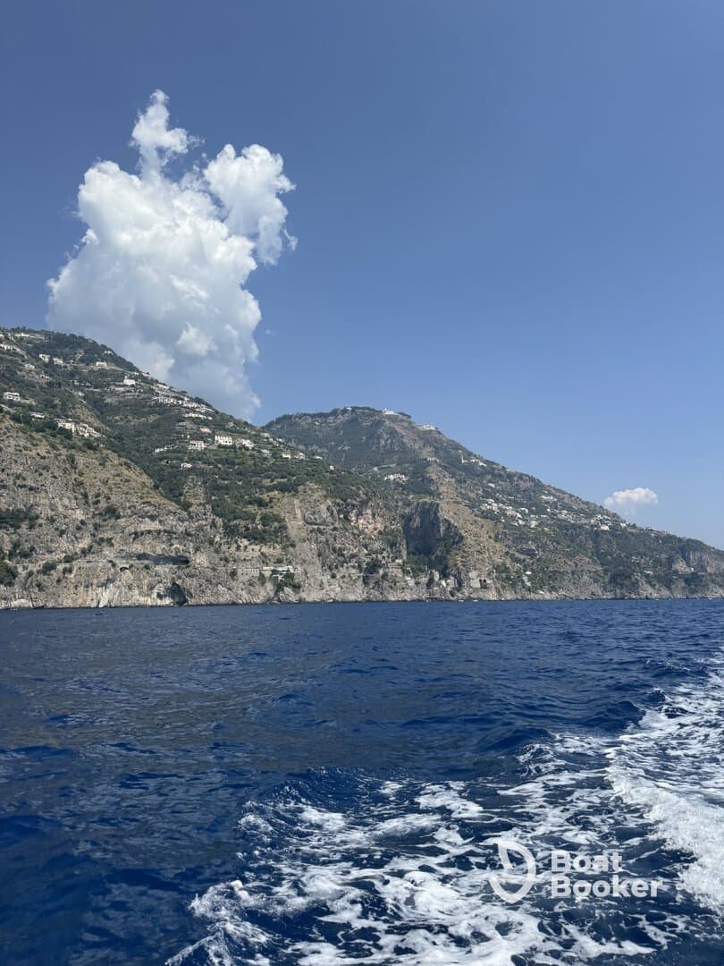 A stunning view of the coastline with lush mountains rising above the deep blue ocean, capturing the beauty of a perfect day on the water.