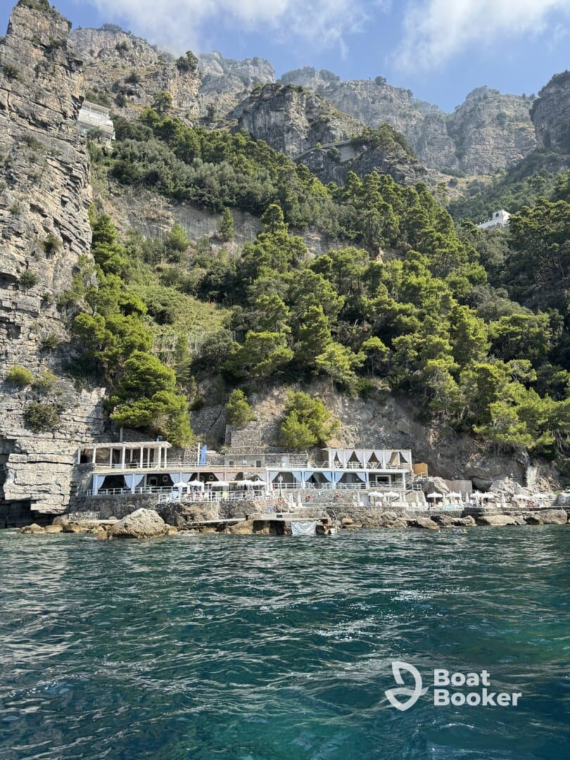 A stunning view of a coastal restaurant nestled among rocky cliffs, showcasing the beautiful scenery of the Amalfi Coast — perfect for dining with a picturesque backdrop.