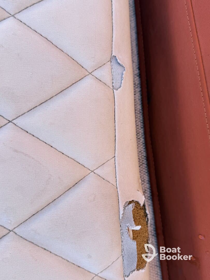 Close-up of a damaged boat cushion, highlighting wear and tear that may require repair or replacement for optimal comfort on board.