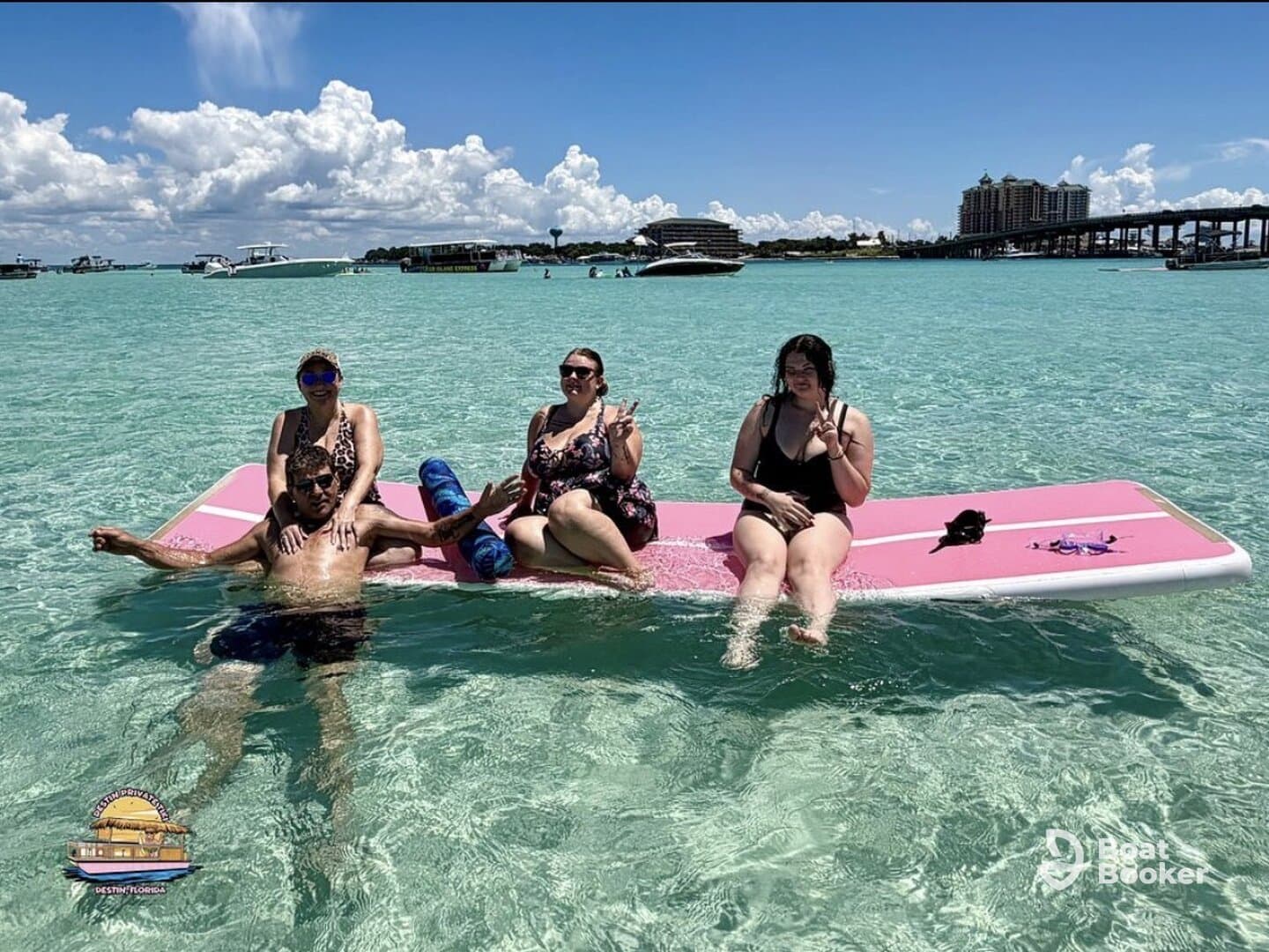 A lively group enjoys a day on a floating mat in crystal-clear waters, perfect for summer fun and relaxation at the beach.