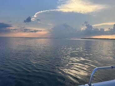 A serene sunset view over calm waters, showcasing the beauty of nature from a boat perspective — perfect for tranquil evening cruises.