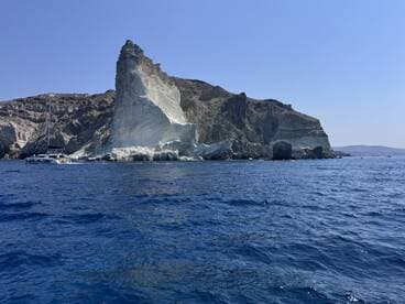 A stunning view of a sailboat navigating past dramatic coastal cliffs, showcasing the natural beauty of the island — perfect for sailing adventures and scenic tours.