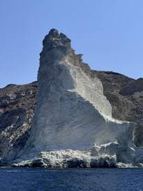 A stunning view of a prominent rock formation against a clear blue sky, showcasing the natural beauty of the coastline — perfect for scenic boat tours.
