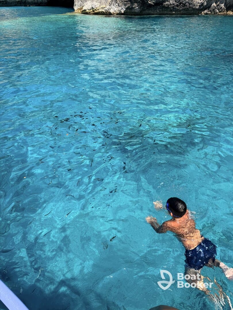 A child swims in the crystal-clear waters, showcasing a perfect day for aquatic adventures and family fun.