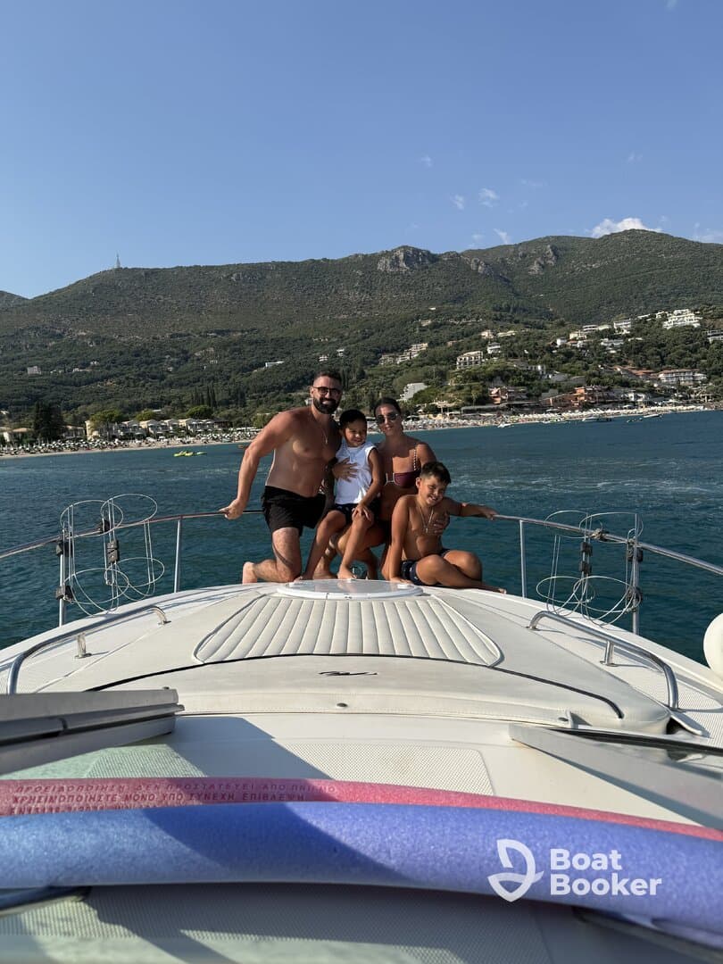 A joyful family poses together on the bow of a boat, enjoying a sunny day on the water — perfect for memorable family outings and adventures.