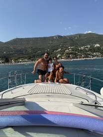 A joyful family poses together on the bow of a boat, enjoying a sunny day on the water — perfect for memorable family outings and adventures.