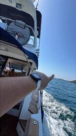 A hand gestures towards the scenic view while aboard a boat, capturing the essence of a fun day on the water with family.