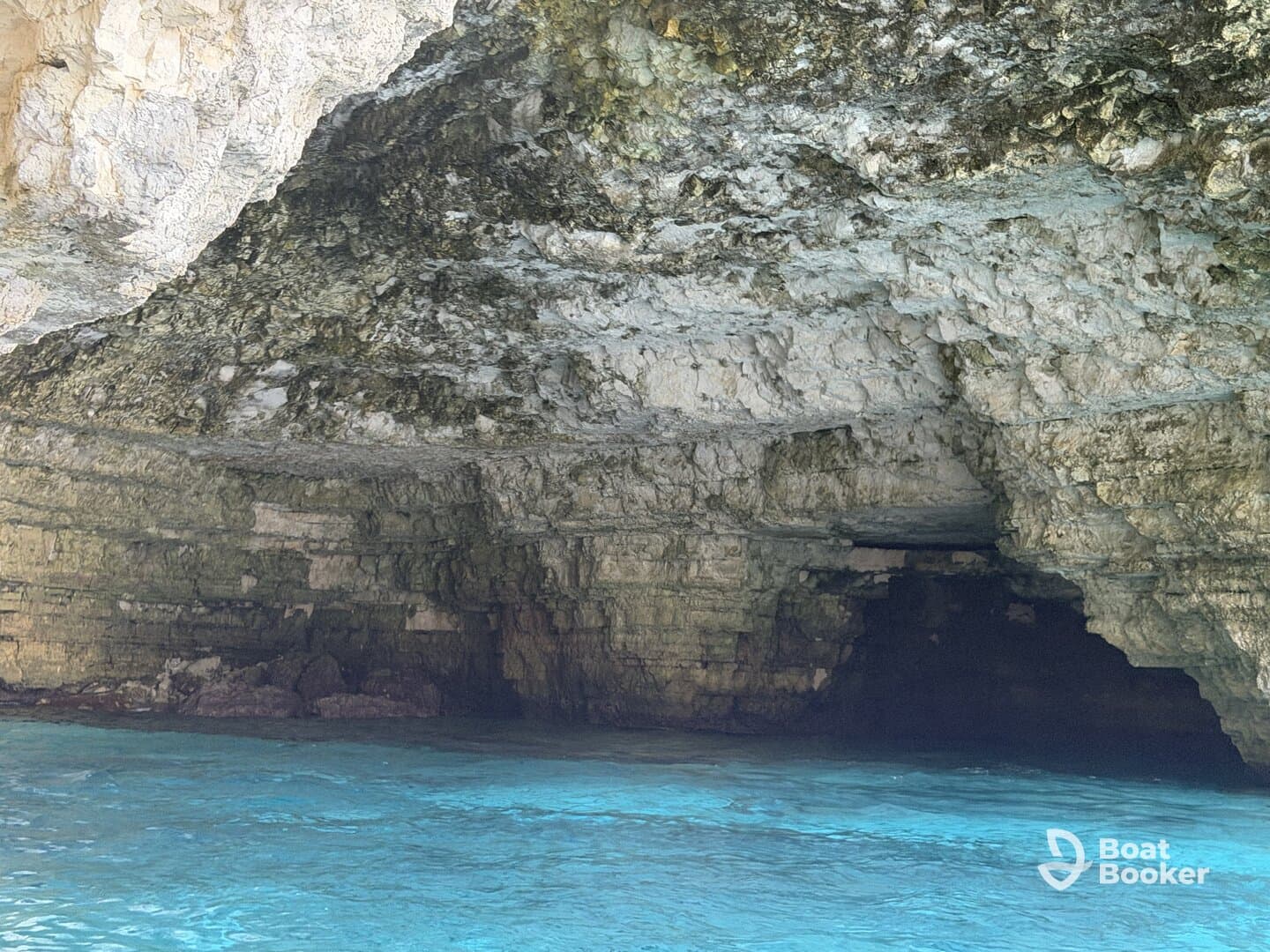 A stunning view of a cave along the coastline, with crystal-clear turquoise waters reflecting the natural beauty of the surroundings — perfect for eco tours and exploration.