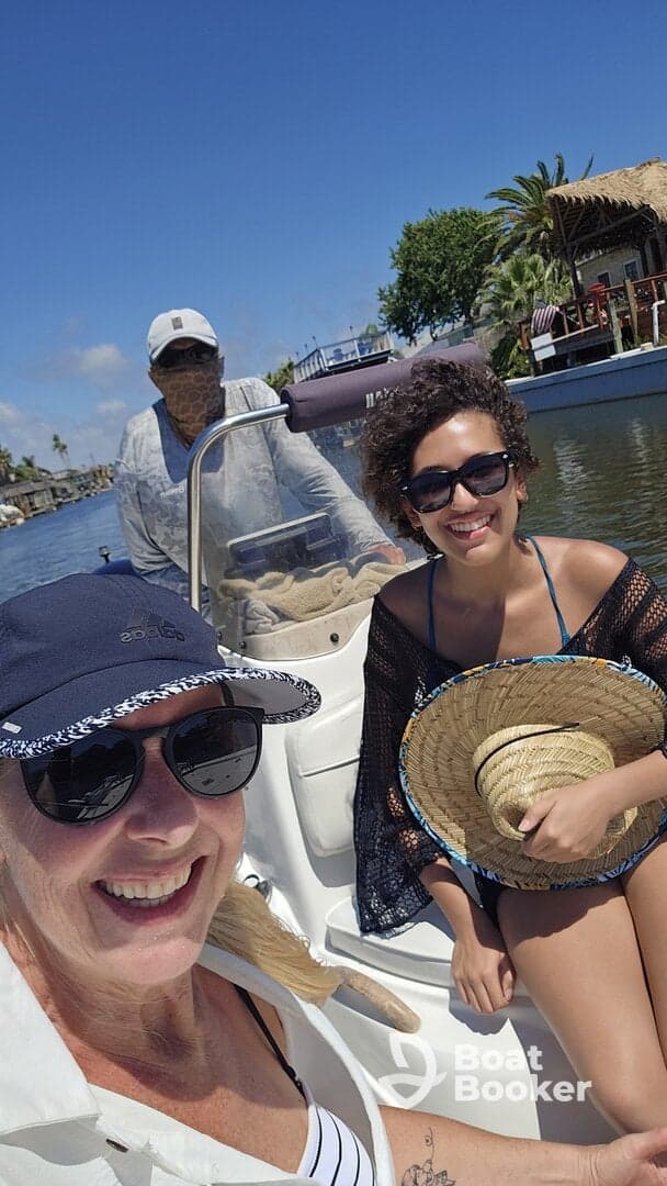 A cheerful group enjoys a sunny day on a boat, capturing the moment with smiles as they navigate through a scenic waterway.