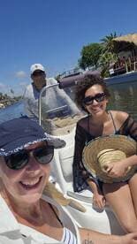 A cheerful group enjoys a sunny day on a boat, capturing the moment with smiles as they navigate through a scenic waterway.