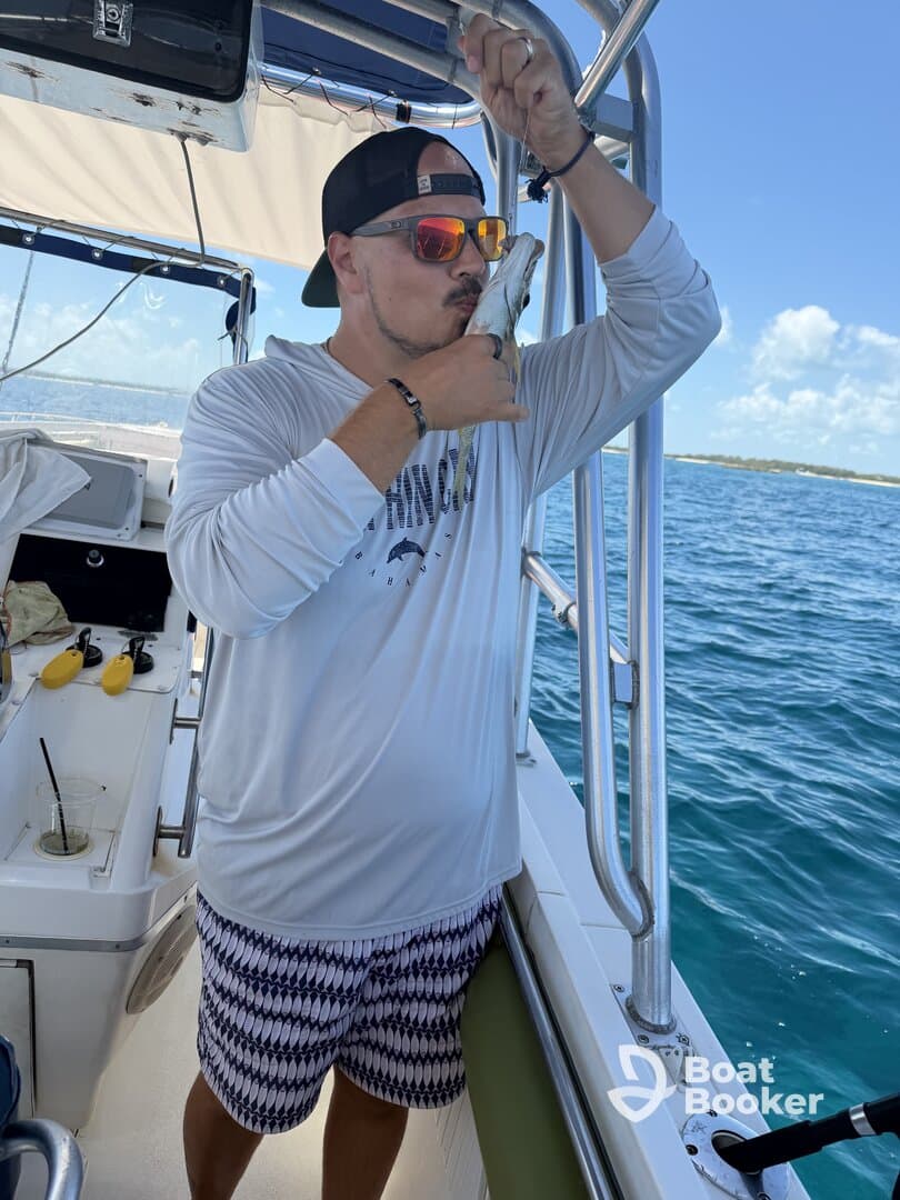 A man joyfully kisses his catch aboard a boat, showcasing the thrill of fishing in the open ocean — a perfect moment for fishing enthusiasts.
