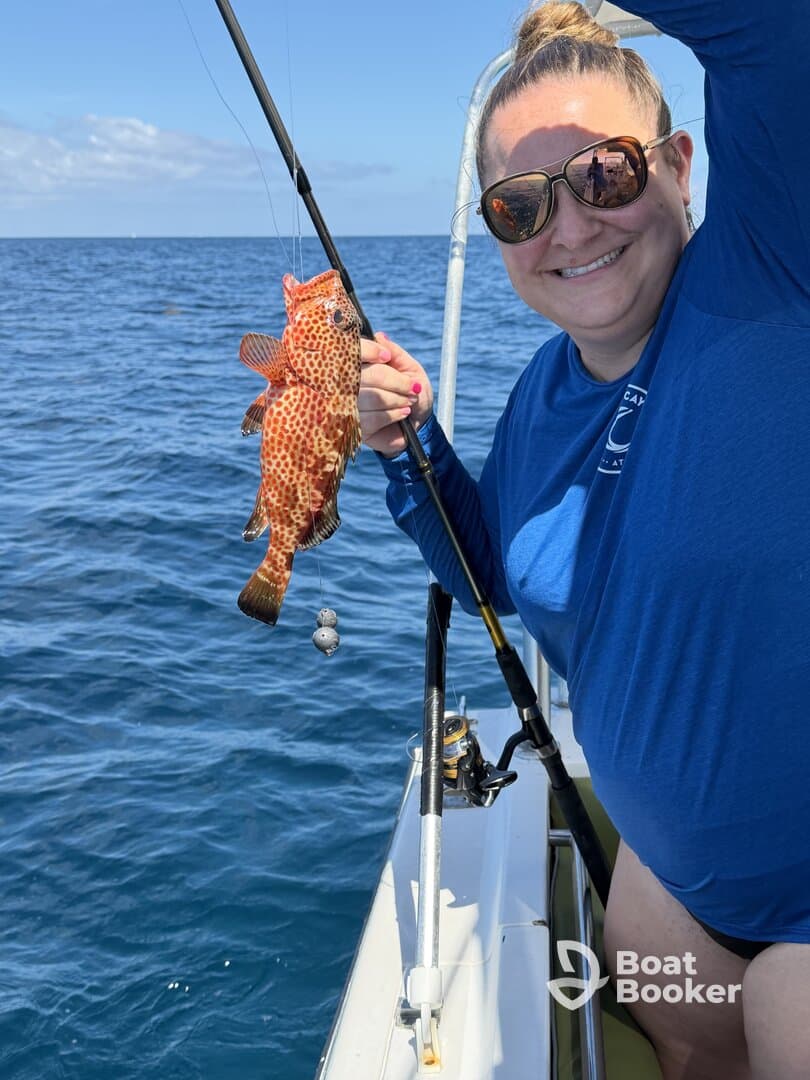 A joyful angler proudly displays her catch while fishing on the open ocean, showcasing the excitement of a day on the water.
