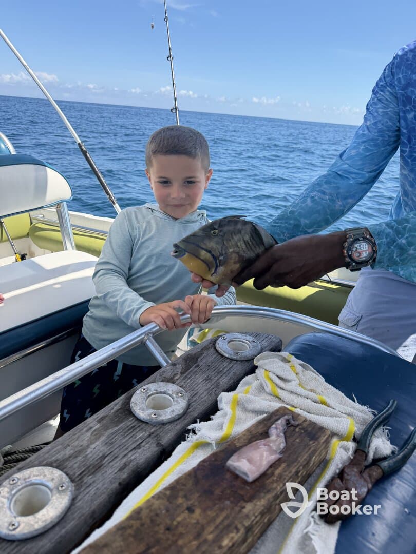 A young boy excitedly holds a fish while fishing on a boat, showcasing a memorable family experience on the water.