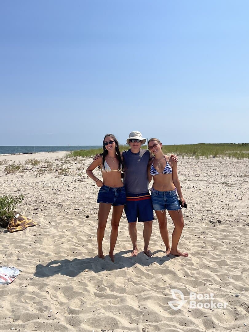 A group of friends poses together on a sunny beach, capturing a moment of fun and relaxation by the water.