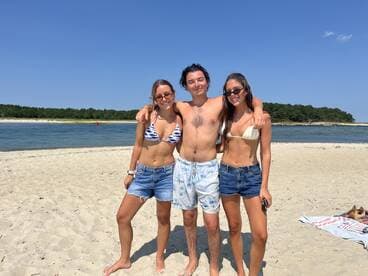 A cheerful group of friends poses together on the beach, enjoying a sunny summer day — perfect for beach outings and memorable moments.