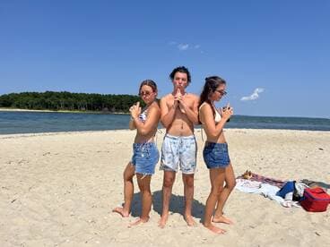 A fun group poses playfully on the beach, showcasing a sunny day of relaxation and enjoyment by the water.