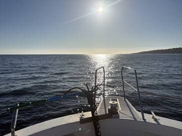 A serene view from the front of a boat, capturing the sparkling water under the sun, perfect for showcasing the beauty of a day on the water.