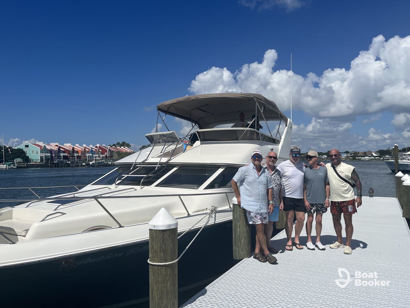 A group of friends poses together on the dock beside a luxurious boat, capturing a moment of camaraderie before their adventure on the water.