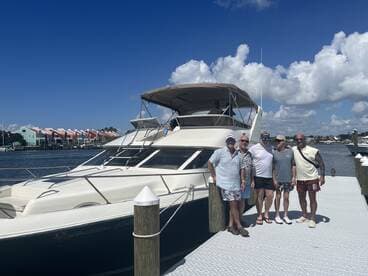 A group of friends poses together on the dock beside a luxurious boat, capturing a moment of camaraderie before their adventure on the water.