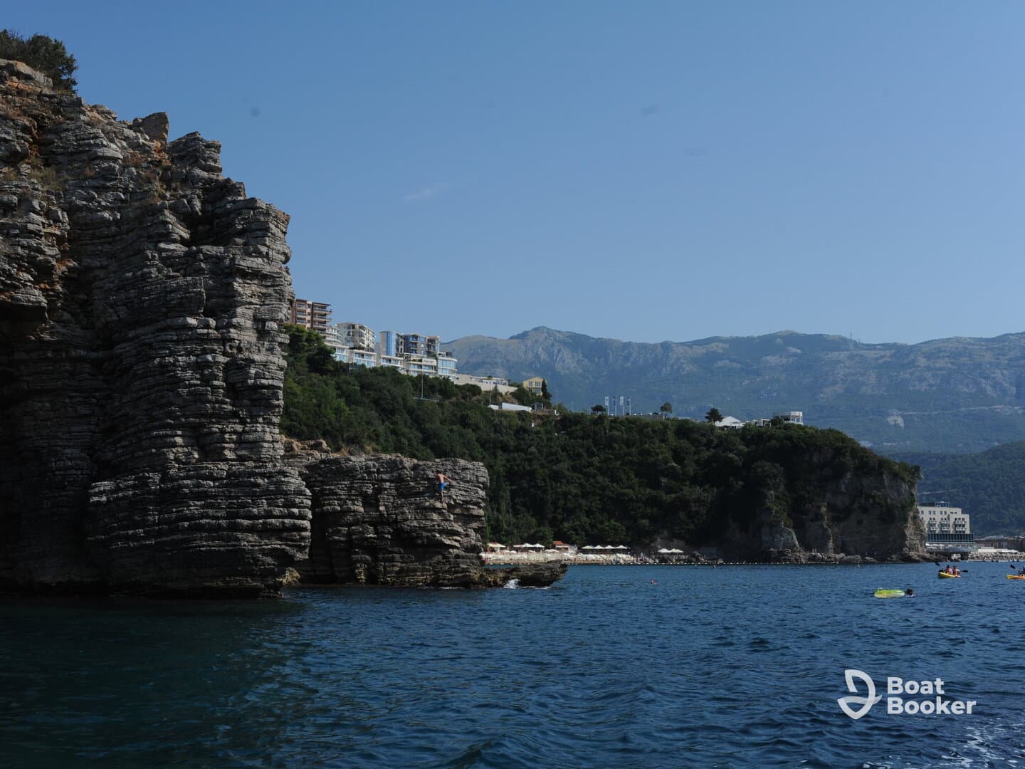 A stunning view of rocky cliffs and a vibrant coastline, with kayakers enjoying the clear waters — a perfect destination for adventure and exploration.