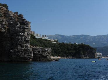 A stunning view of rocky cliffs and a vibrant coastline, with kayakers enjoying the clear waters — a perfect destination for adventure and exploration.