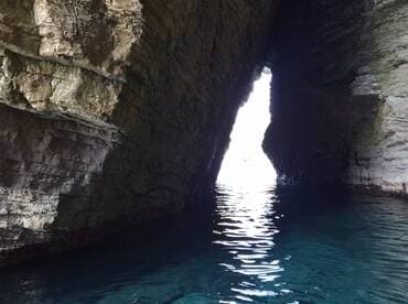 A stunning view of a natural cave opening, revealing bright light and tranquil waters — a perfect representation of coastal exploration.