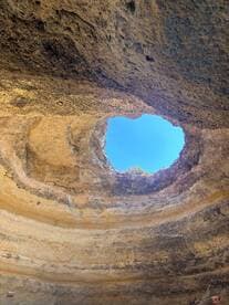 An abstract view of a rock formation with a hole leading to the sky, showcasing natural geological features.