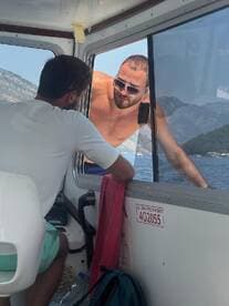 Two men engage in conversation aboard a boat, showcasing the camaraderie and experiences shared on the water. The scenic backdrop hints at a beautiful day out at sea.