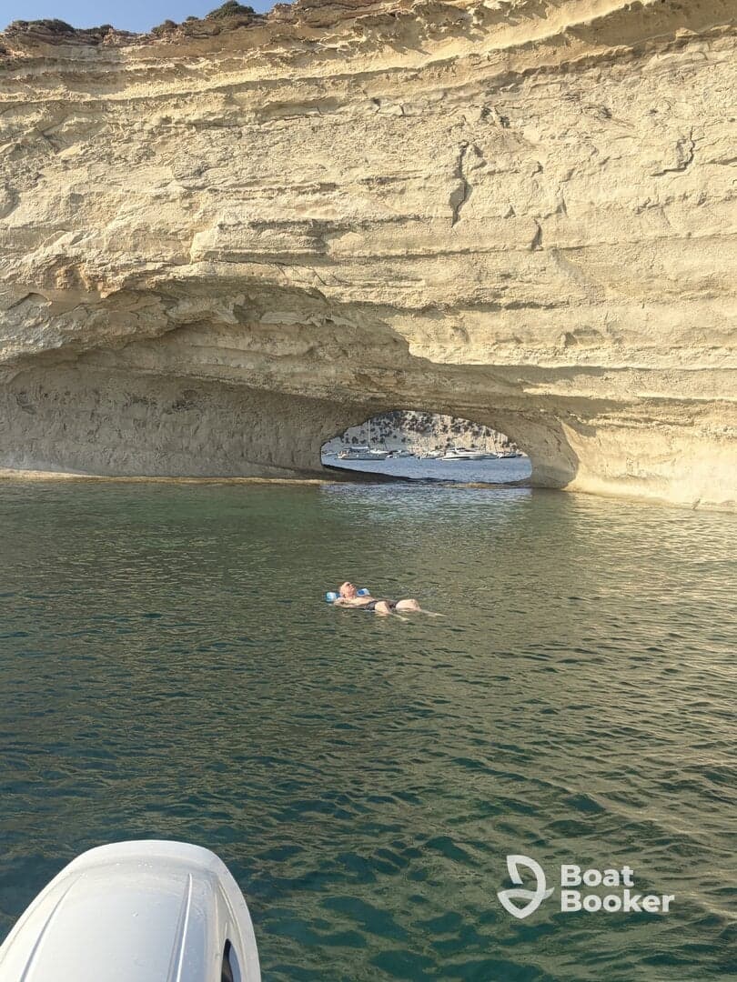 A person floats peacefully in the clear waters near a stunning rock formation, showcasing a perfect blend of relaxation and natural beauty — ideal for a day of swimming and exploration.