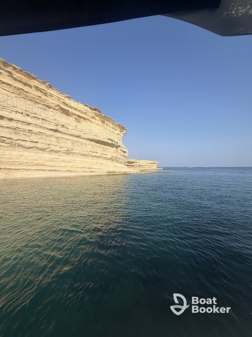 A stunning view of a rocky coastline against a clear blue sky, showcasing the natural beauty of the area — perfect for scenic boat tours.