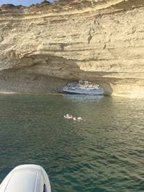 A person floats peacefully in the clear waters near a stunning rock formation, showcasing a perfect blend of relaxation and natural beauty — ideal for a day of swimming and exploration.