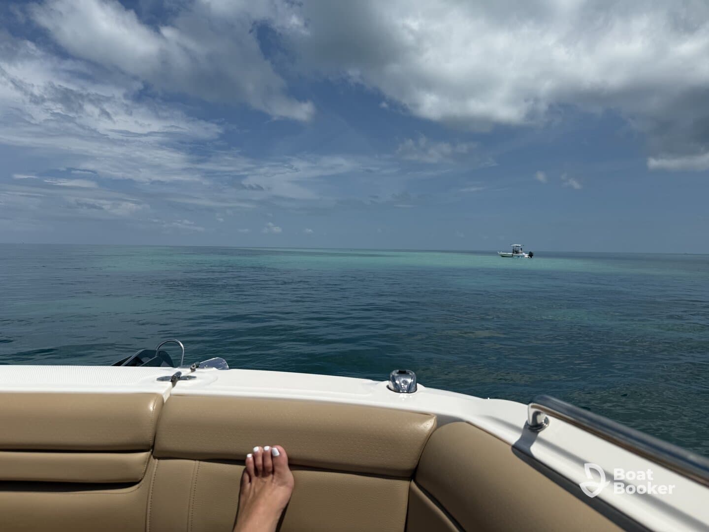 A serene view from the deck of a boat, showcasing calm ocean waters and a distant vessel — perfect for a relaxing day on the water.