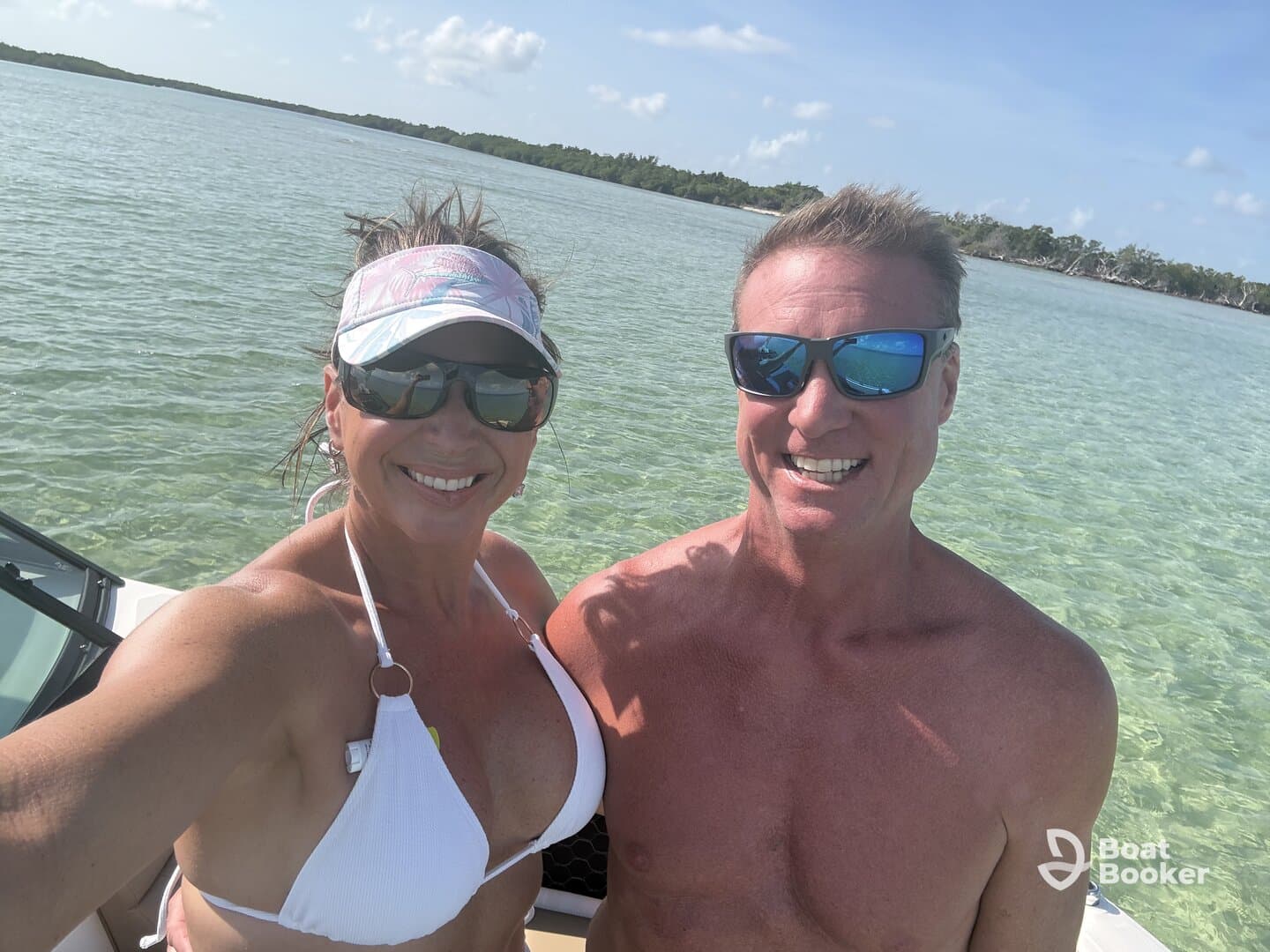 A cheerful couple takes a selfie on a sunny day by the water, showcasing their fun boating adventure.