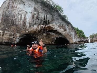 A snorkeler gives a thumbs up while exploring a stunning cave in the ocean, showcasing the excitement of underwater adventures.