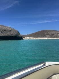A stunning view of a secluded beach and rocky coastline, showcasing the vibrant turquoise waters — perfect for exploring hidden gems by boat.