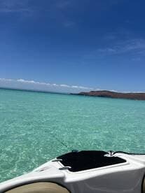 A stunning view of a boat anchored in crystal-clear waters, showcasing the serene beauty of the surrounding landscape and inviting turquoise hues.