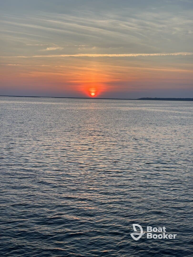 A stunning sunset over calm waters, creating a picturesque scene perfect for evening boat cruises.