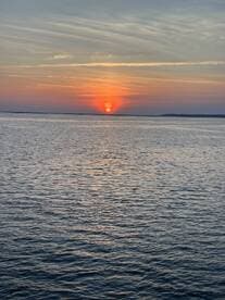 A stunning sunset over calm waters, creating a picturesque scene perfect for evening boat cruises.