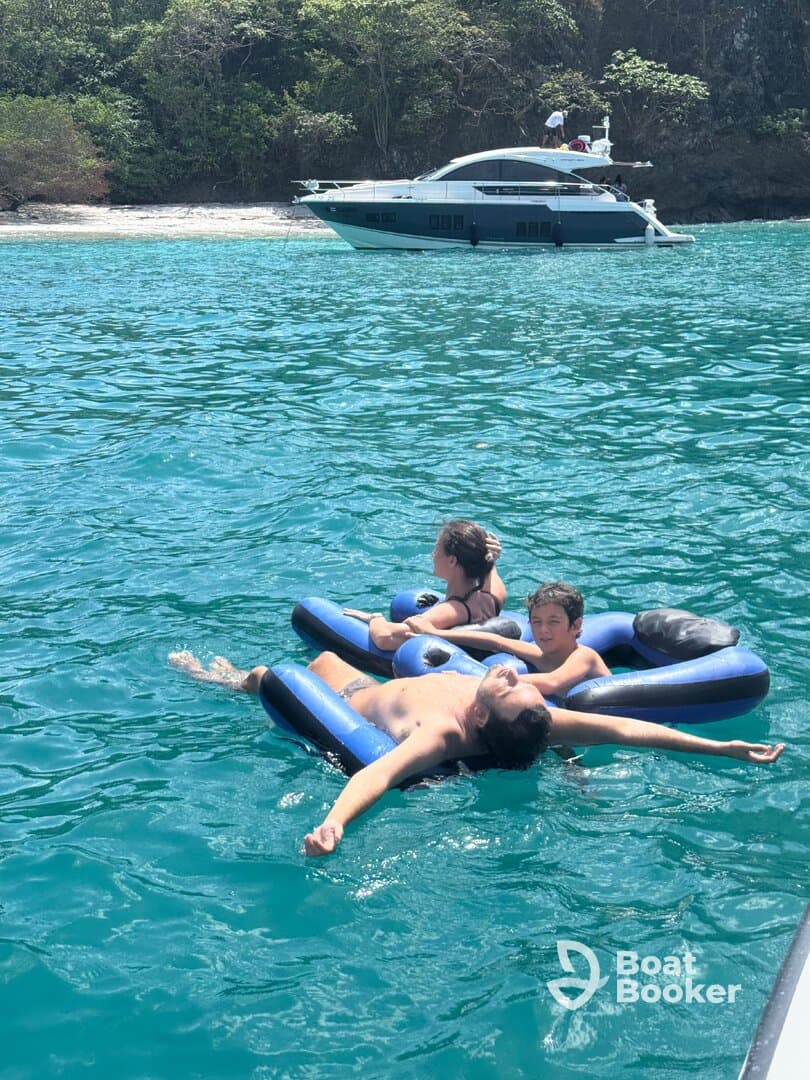A family enjoys a relaxing day on the water, floating on inflatable loungers while a yacht is anchored nearby — perfect for summer fun and family bonding.