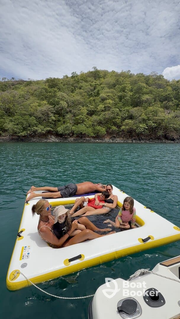 A joyful family enjoys a day on a floating mat in clear waters, creating unforgettable memories under the sun.