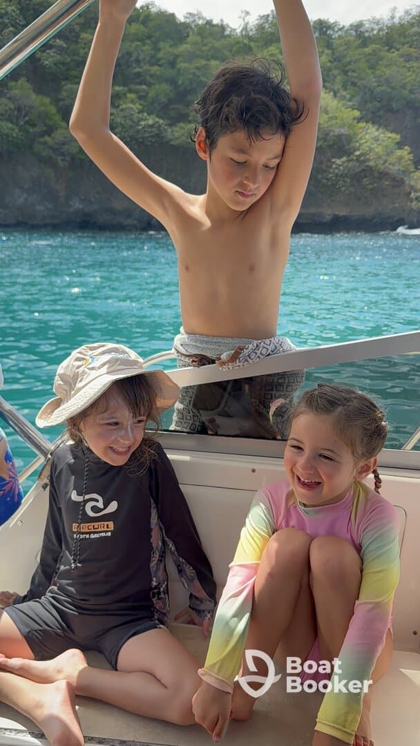 Three children enjoy a joyful moment aboard a boat, laughing and playing in the sun — a perfect snapshot of family fun on the water.
