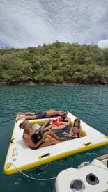 A joyful family enjoys a day on a floating mat in clear waters, creating unforgettable memories under the sun.