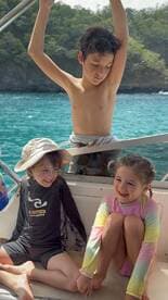Three children enjoy a joyful moment aboard a boat, laughing and playing in the sun — a perfect snapshot of family fun on the water.