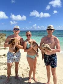 Three friends enjoy a unique experience on the beach, holding adorable pigs — a memorable wildlife encounter in the Bahamas.
