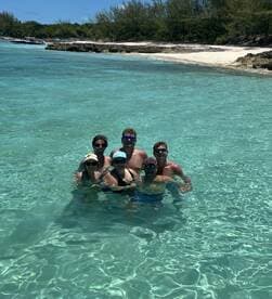 A cheerful group of friends enjoys a refreshing swim in crystal-clear waters, capturing the essence of fun and relaxation during their beach day.