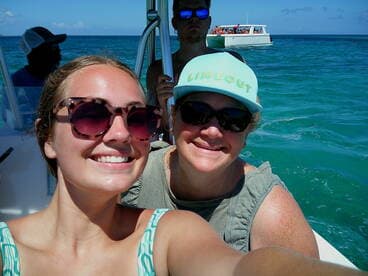 Two friends take a cheerful selfie on a boat with a beautiful ocean backdrop, capturing the joy of their boating adventure.